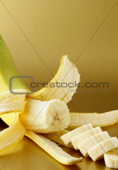 ripe banana cut into slices on a gold background