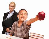 Hispanic Student Boy At Desk with Apple and Female Adult Behind.