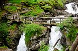 Wooden bridge over Saent waterfalls in the Italian mountains