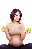 beautiful pregnant woman holding an orange and an apple in her hands