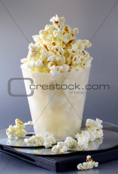 cup of popcorn and DVD disks on a gray background