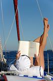 Young woman reading and sunbathing on sail boat