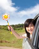 happy little girl holding windmill in the car
