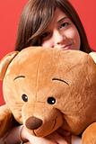 Young woman embracing teddy bear sitting close-up