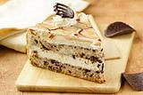 piece of cream  caramel cake with chocolate on a wooden board