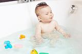 Cute baby playing with water and showing tongue while taking a bath