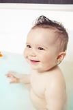 CuteCute baby sitting in the water, having fun and smiling while taking a bath 