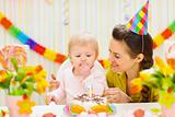 Portrait of happy mom and baby eating birthday cake