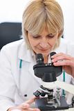Senior female researcher looking in microscope
