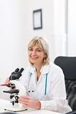 Smiling senior doctor woman working with microscope at laboratory
