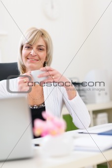 Smiling senior business woman having coffee break
