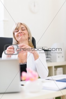 Senior business woman having cup of coffee and dreaming about vacation