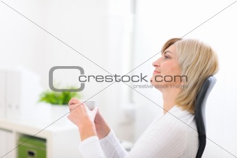 Portrait of dreaming senior business woman with cup of coffee