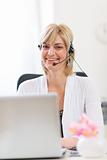 Smiling senior business woman with headset working on laptop
