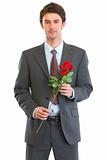Portrait of happy man in suit with rose in hand