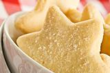Sugar coated shortbread cookies in star shapes stacked up - on a white background with space for text