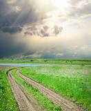 rural road in green grass under dramatic sky