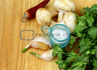 garlic,mushrooms, chili pepper, parsley, cucumber and spices on a cutting board