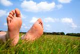 relaxed foot on grass with cloud background