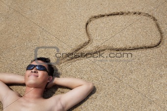smiling young man lying on the beach and dialog symbol