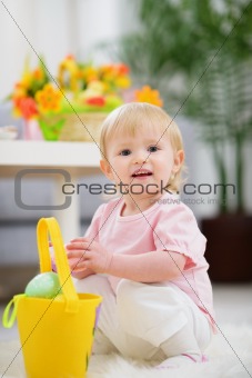 Baby gathering Easter eggs in basket
