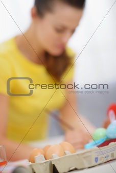 Closeup on eggs and woman making decoration to Easter in background