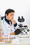 Closeup on microscope and medical doctor in background
