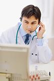 Medical doctor in headset working in office