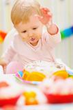 Eat smeared baby having fun with birthday cake