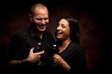Happy Young Mixed Race Couple Holding Wine Glasses Against A Black Background.