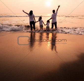 happy family  holding hands on beach and watching the sunset