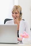 Happy senior business woman with headset working on laptop
