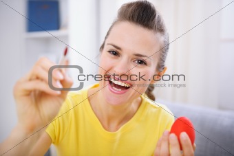 Smiling woman painting on Easter egg
