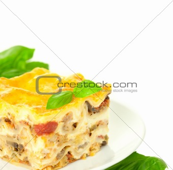Portion of Classic Lasagna Bolognese with basil herb / isolated 