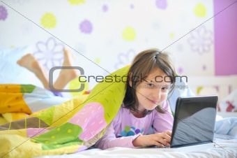 Teen girl in her bed looking on laptop 