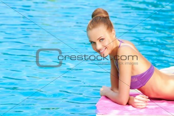 Young woman in swimsuit lying close to pool