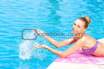 Happy woman splashing water in pool