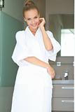 Relaxed woman standing in white bathrobe