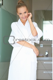 Relaxed woman standing in white bathrobe