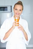 Woman in bath robe drinking orange juice