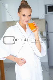 Woman in bath robe drinking orange juice