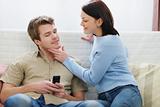 Young woman trying to distract boyfriend from mobile phone