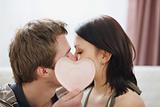 Kissing couple hiding behind Valentines heart