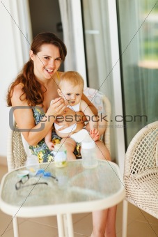 Young mama feeding baby on terrace