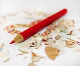 Sharp red pencil among pencils shavings on white background