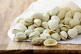 pistachio nuts in a white shell on a wooden board