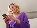 Happy young woman typing text message on mobile phone