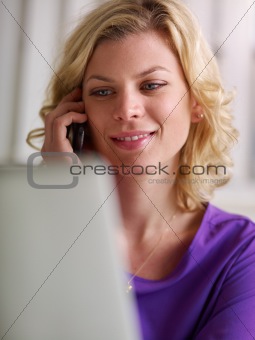 Young woman working with pc and speaking on the phone