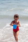 Little Girl Playing with a Bucket on the Beach