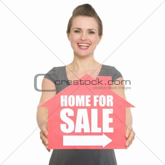 Portrait of smiling realtor showing home for sale sign isolated